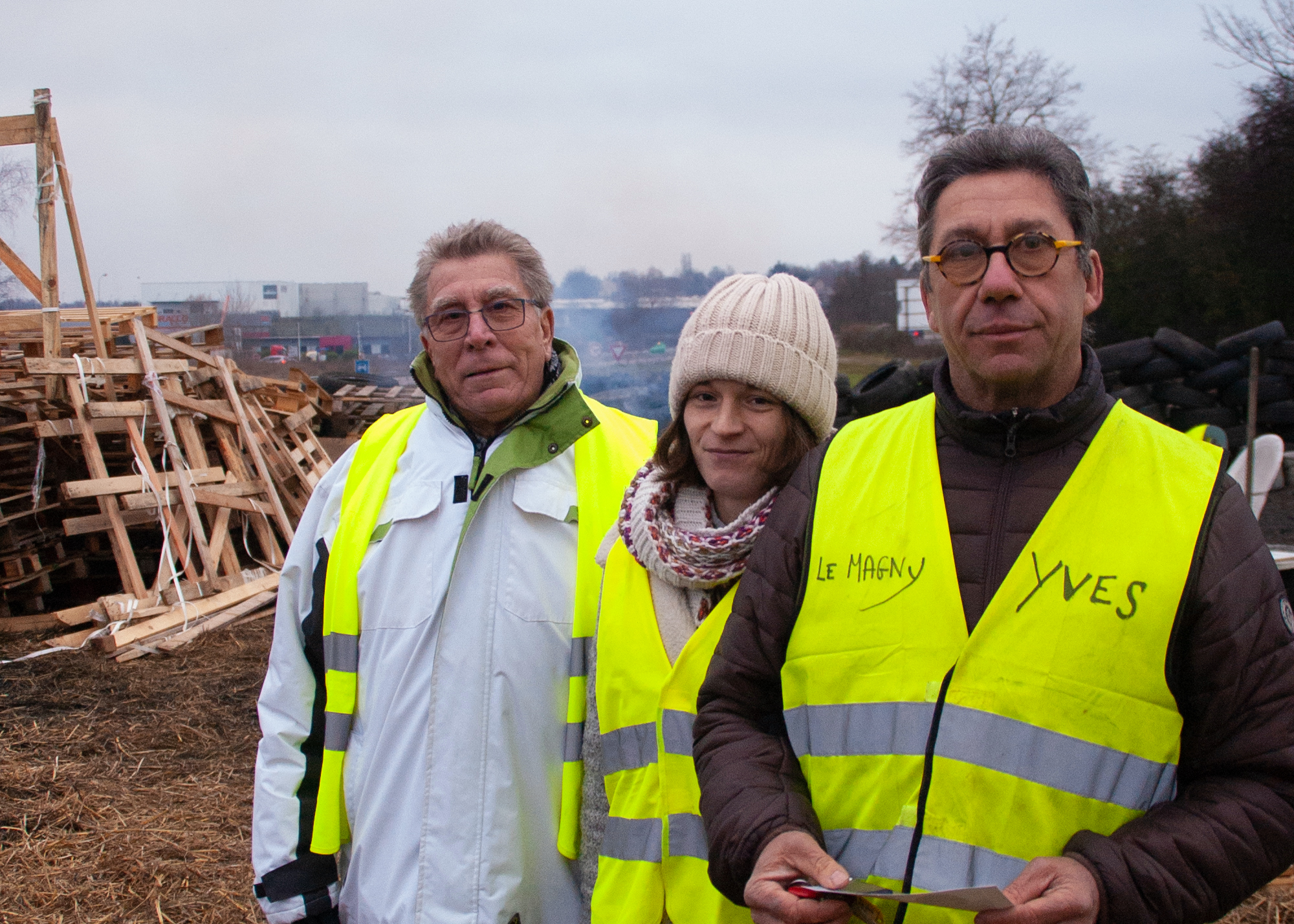 Three people in yellow vests stand and look at the camera